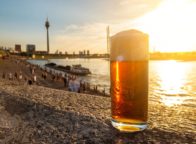 Een glas Altbier met uitzicht op de rijn in Düsseldorf tijdens de zonsondergang