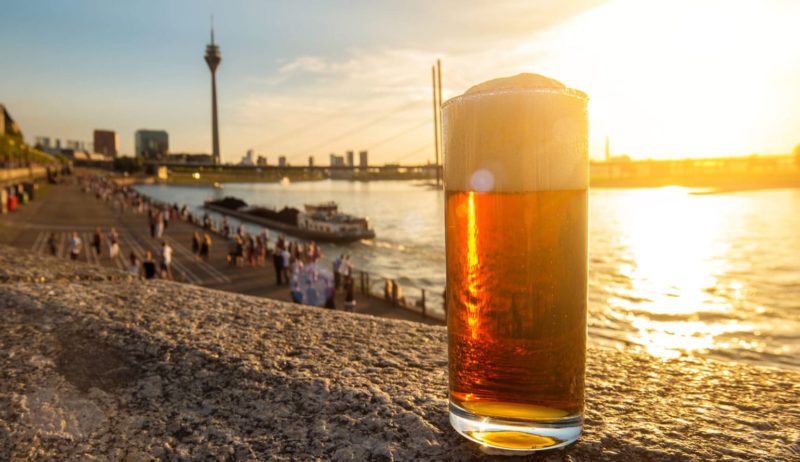 Een glas Altbier met uitzicht op de rijn in Düsseldorf tijdens de zonsondergang