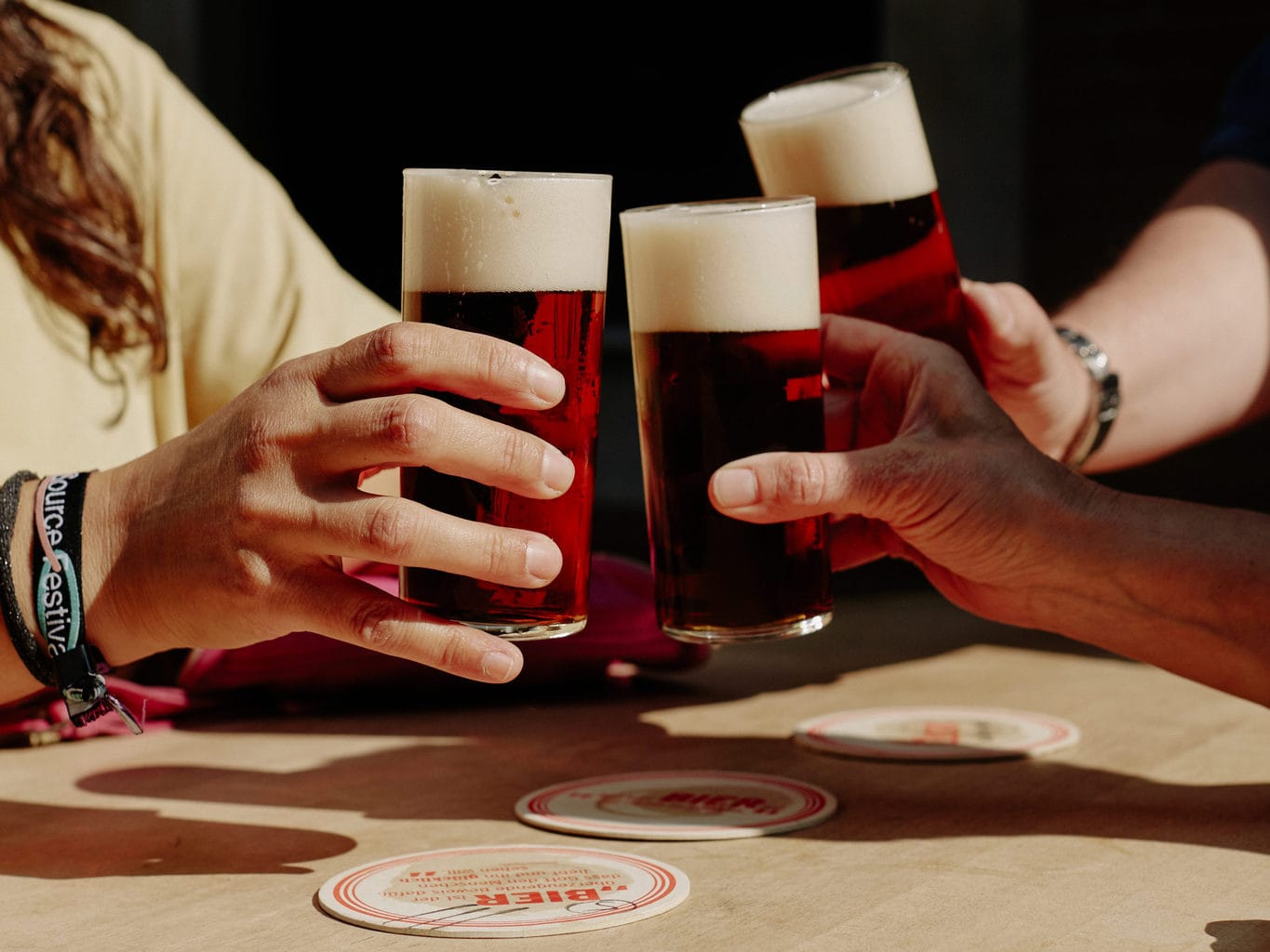 Drie mensen proosten met een glas Altbier in Düsseldorf