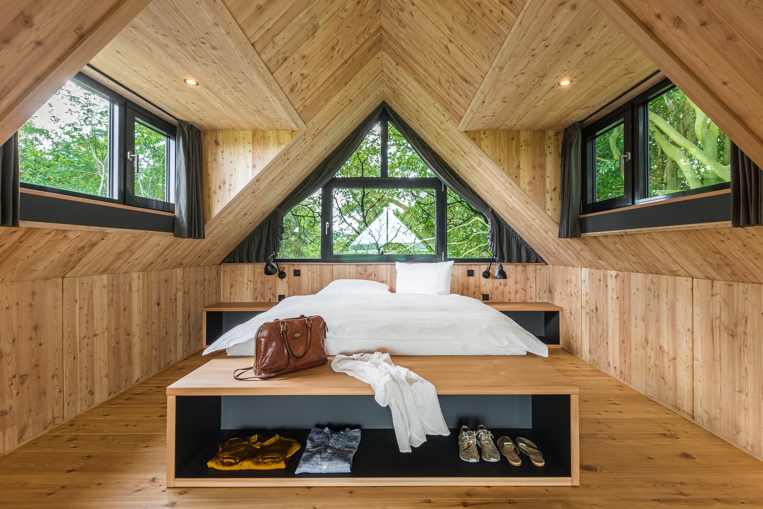 Slaapkamer in het boomhuis van Hotel Lütetsburg Lodges in Nedersaksen met veel hout