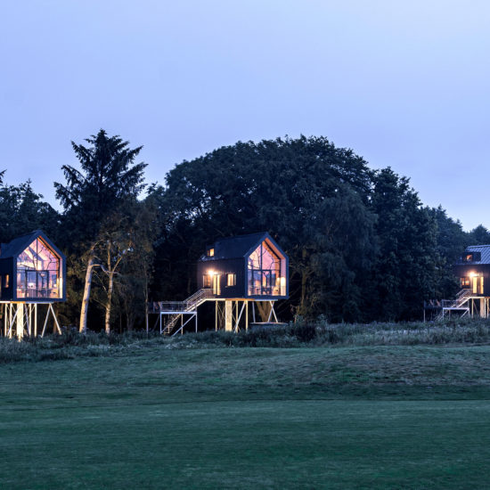 Drie boomhuizen van Hotel Lütetsburg Lodges in Nedersaksen met avondstemming