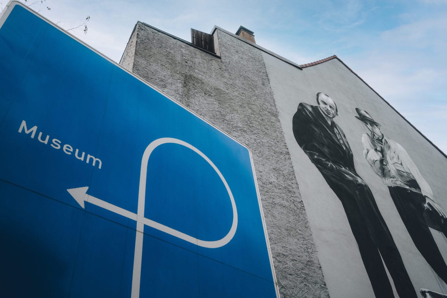 Graffiti met kunstenaar Joseph Beuys en een bord dat wijst naar de ingang van een museum in Mönchengladbach
