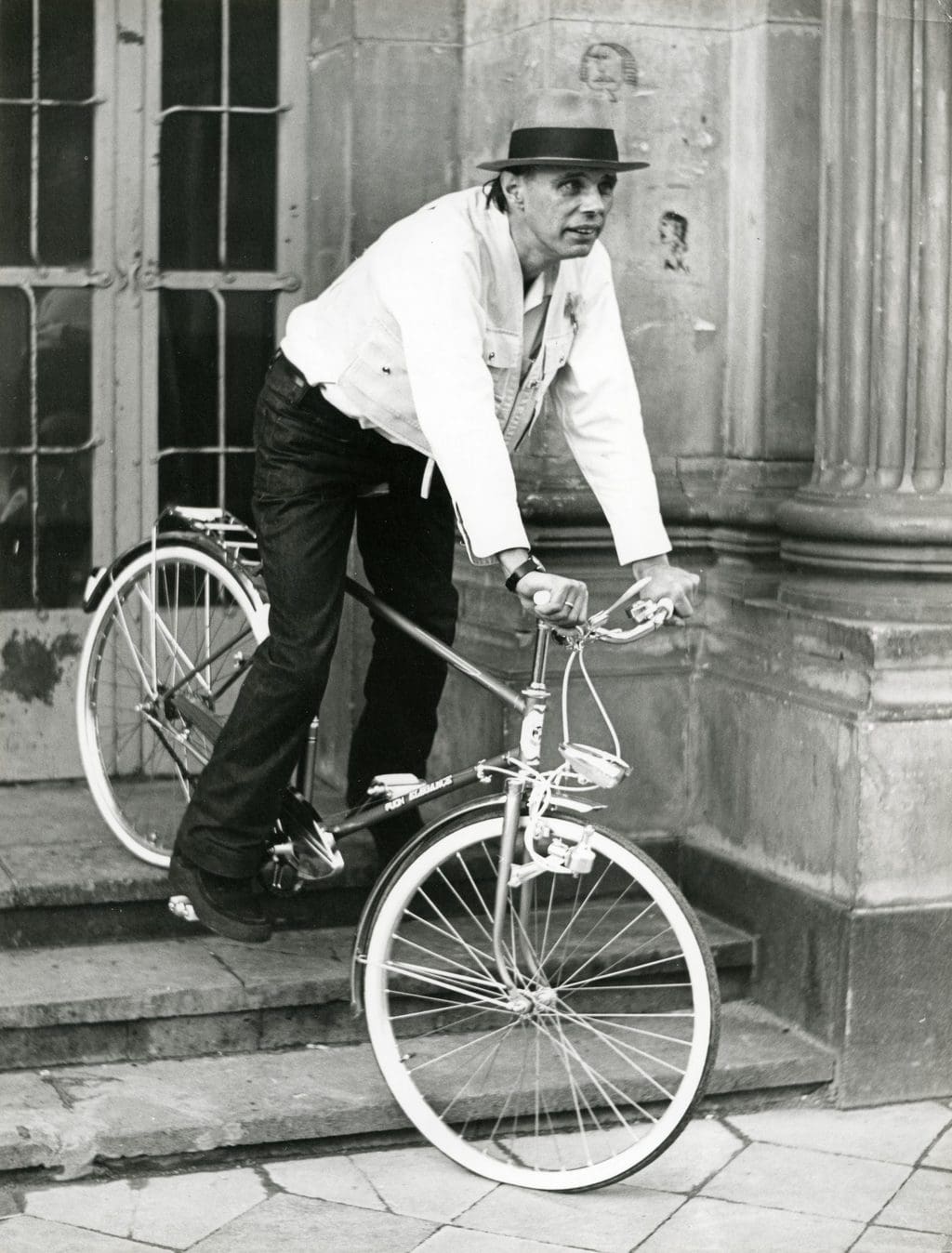Kunstenaar Joseph Beuys op een fiets