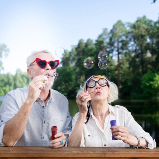 Een stel bestagers maakt zeepbubbels met een hartjesbril