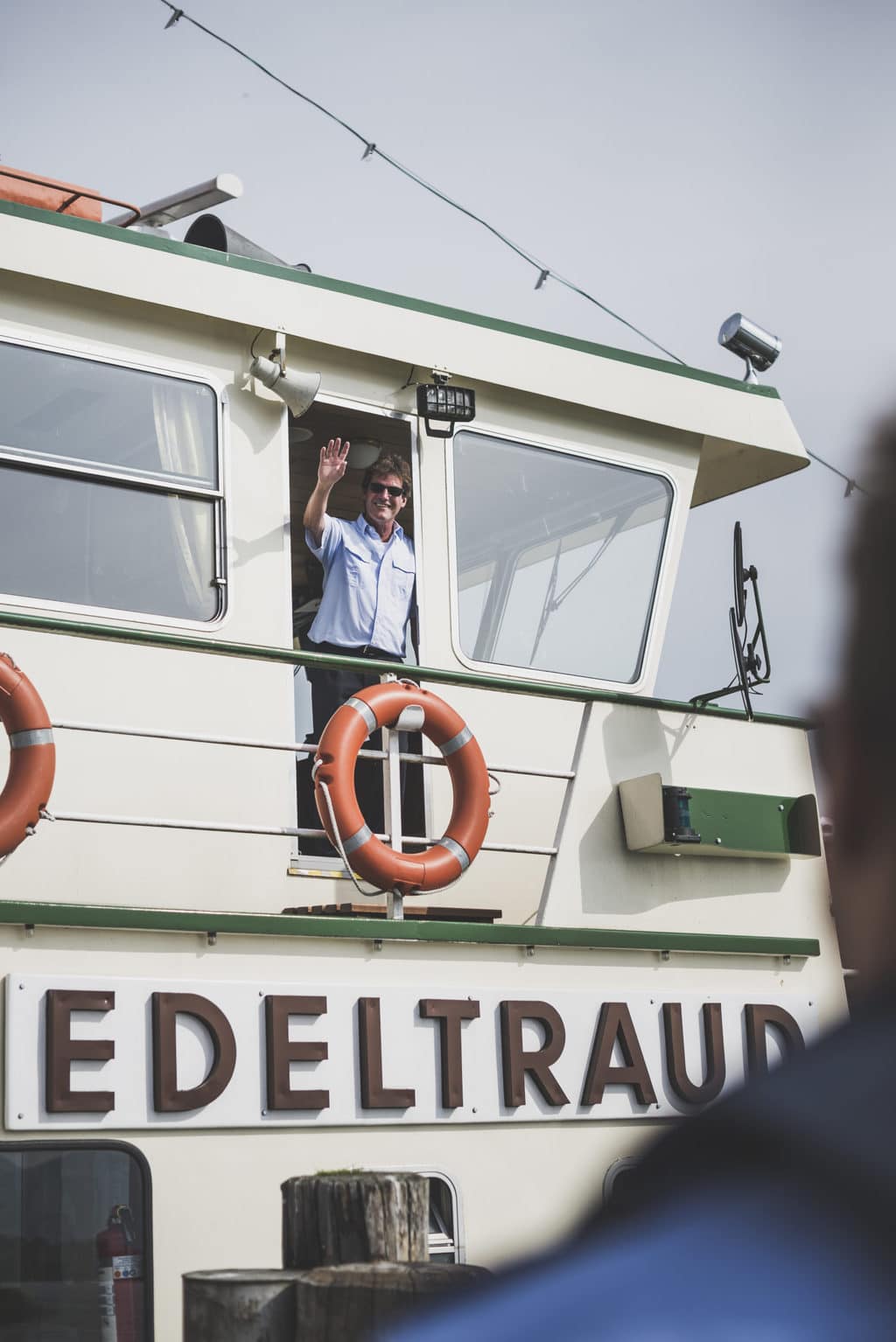Kapitein Otto Strasser zwaait vanaf zijn boot Edeltraut op de Chiemsee