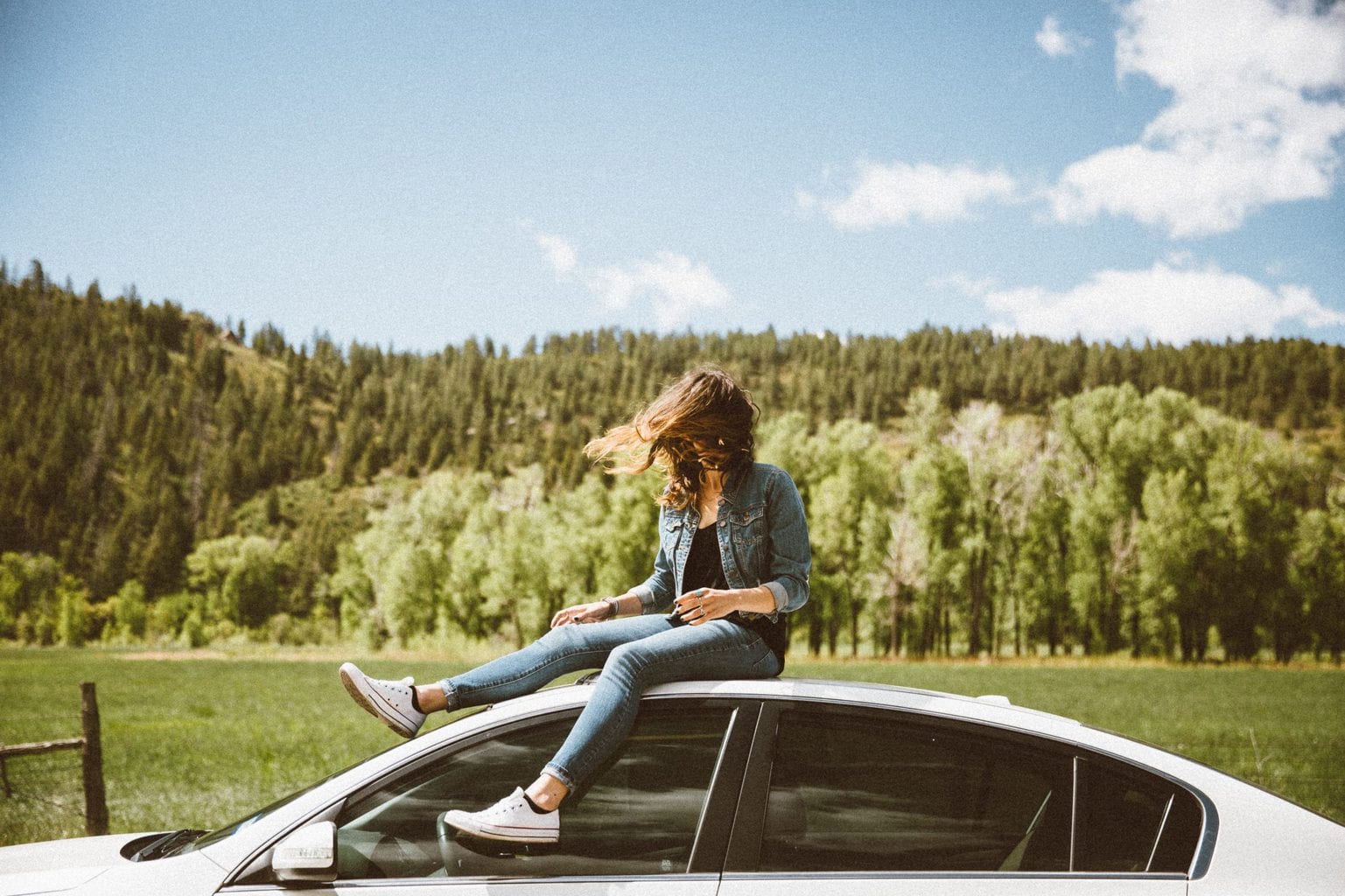 Vrouw zit op een autodak tijdens een road trip
