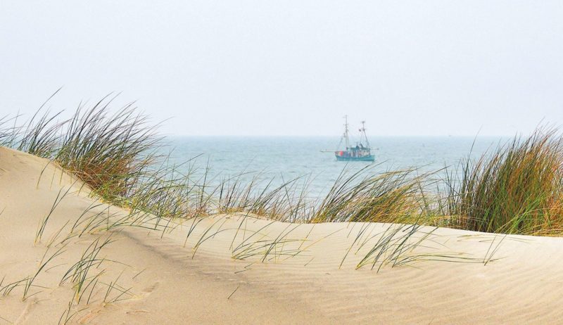 Een vissersboot achter de duinen van Spiekeroog