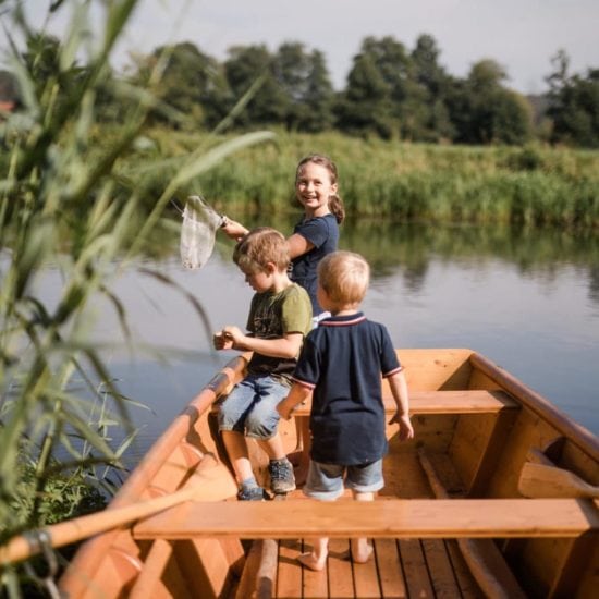 Kinderen spelen in een boot op het water bij een van de vakantieboerderijen in Beieren