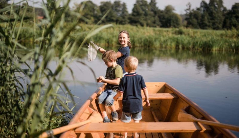 Kinderen spelen in een boot op het water bij een van de vakantieboerderijen in Beieren