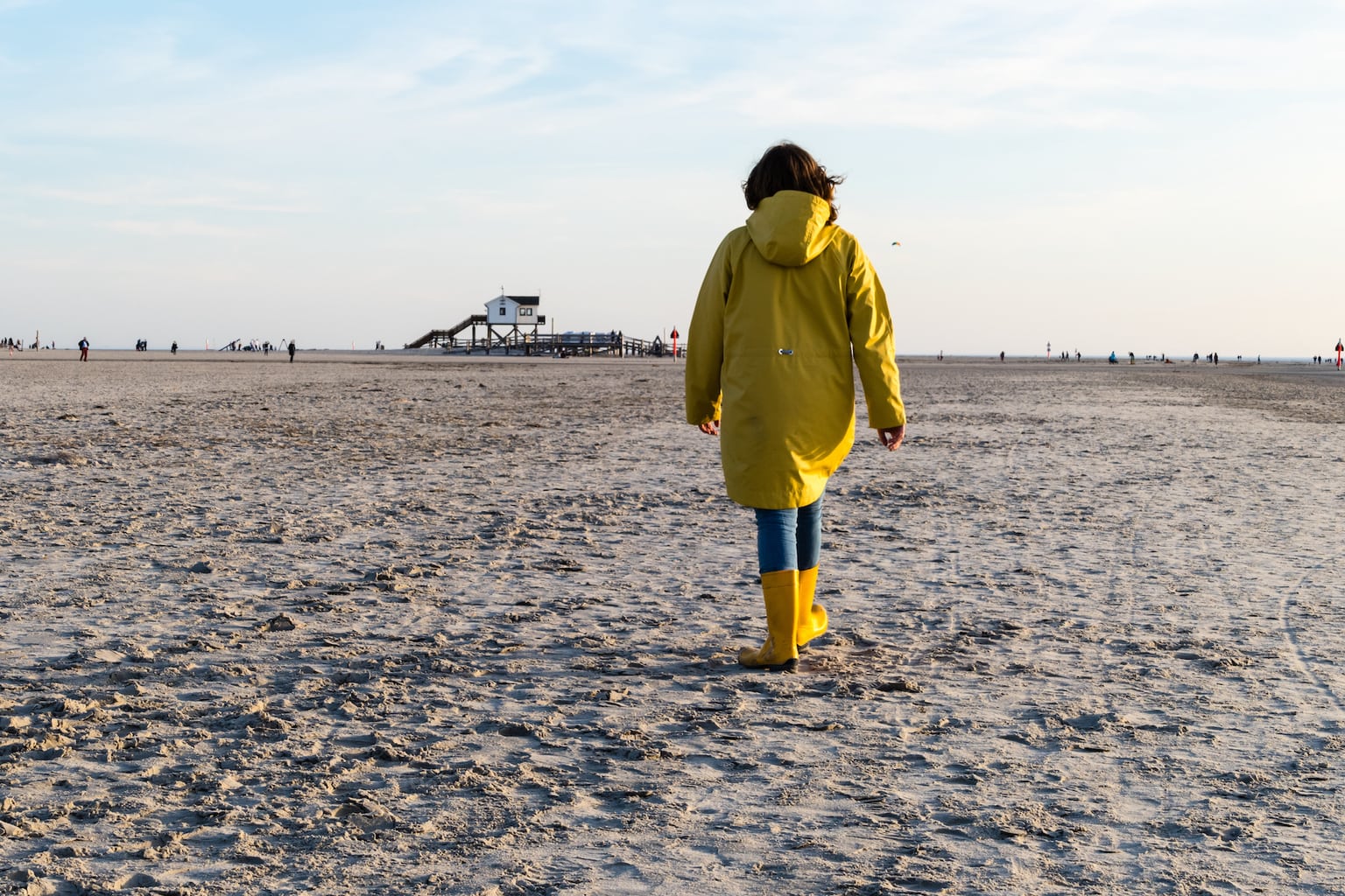 Vrouw in een regenjas op het strand van St. Peter Ording in Sleeswijk Holstein