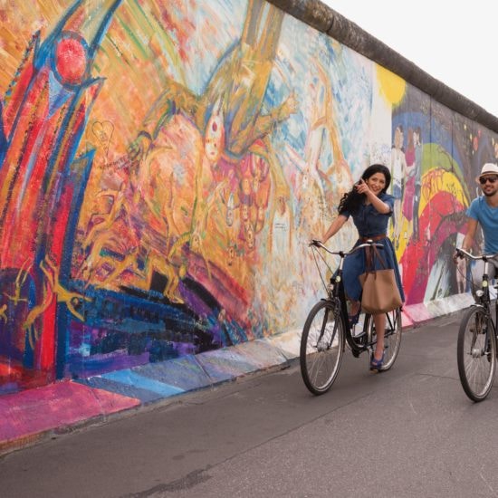 Spaanse touristen fietsen langs de East Side Gallery in Berlijn