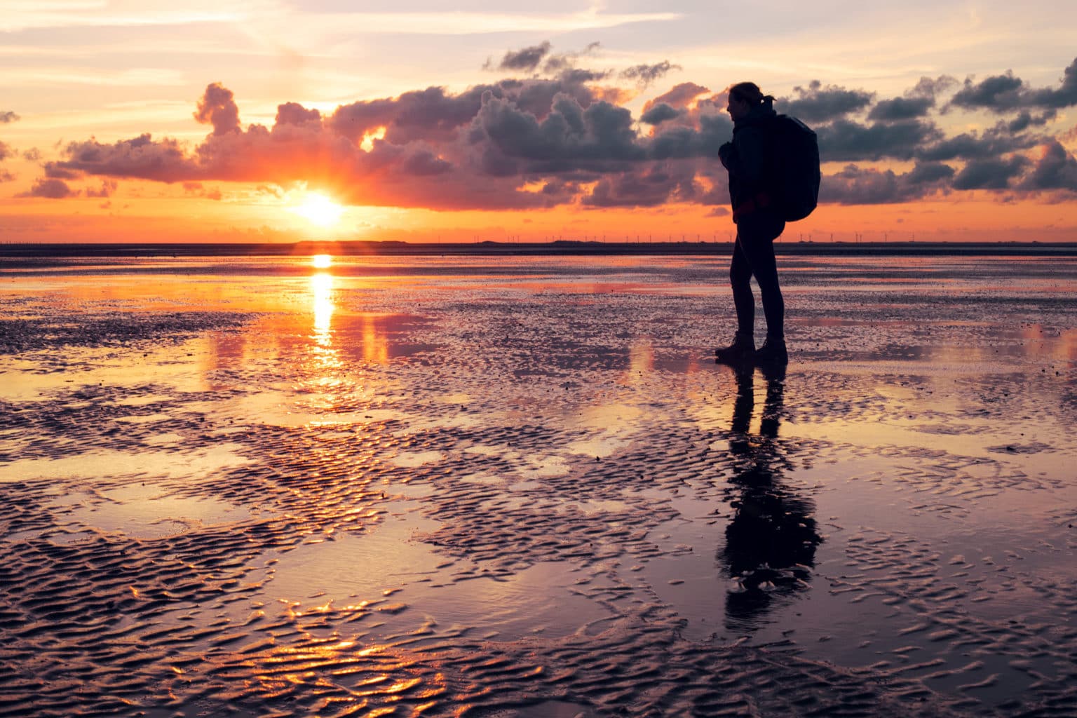 Wandelaar op het was op het Duits eiland Borkum tijdens zonsondergang