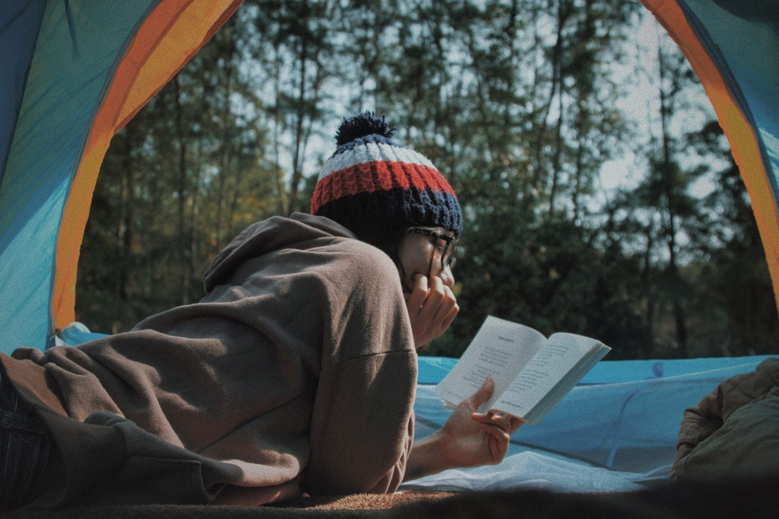 Een jonge vrouw leest onstpannen in haar boek in een tent