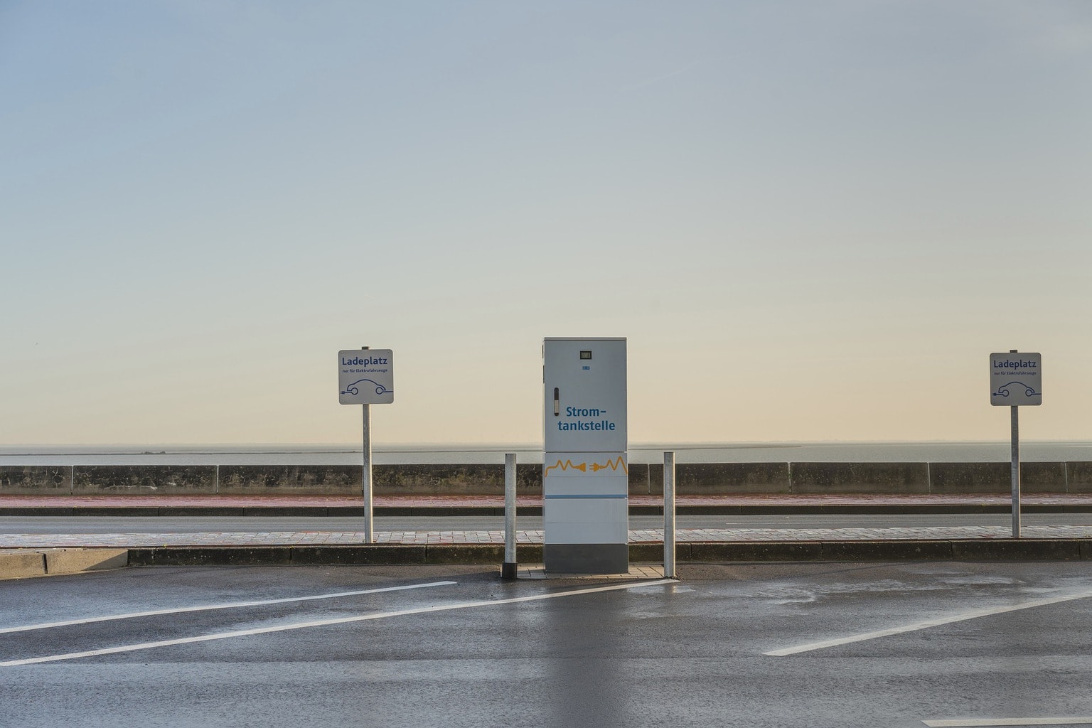 Een tankstation voor elektrische autos in Duitsland met op de achtergrond de zee