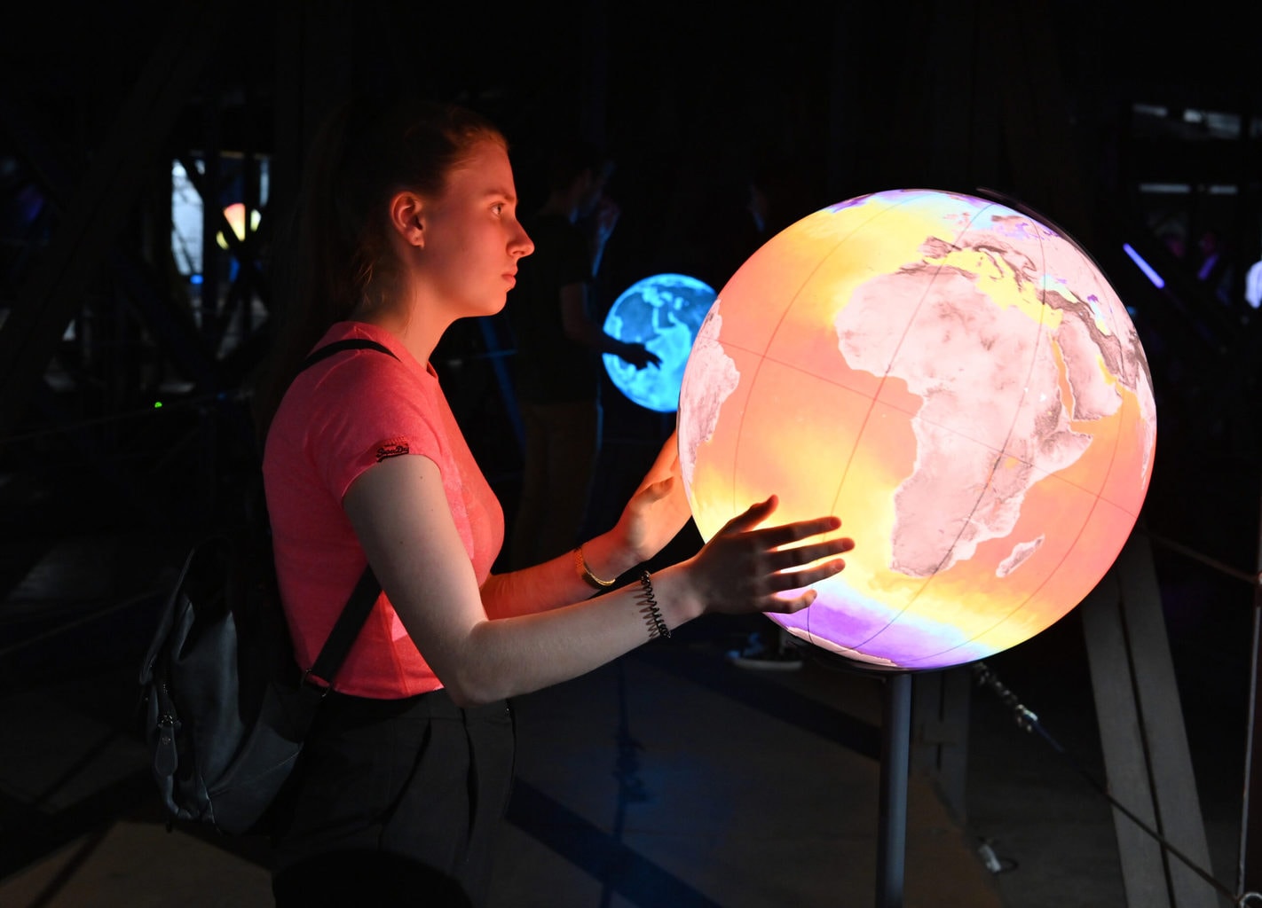 Een jonge vrouw kijkt naar een globus terwijl ze de tentoonstelling in Gasometer Oberhausen bezoekt