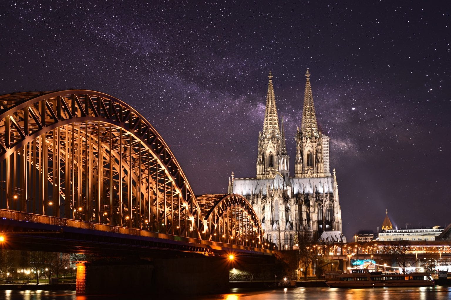 De Keulse dom met de Hohenzollernbrug en de Rijn in het donker