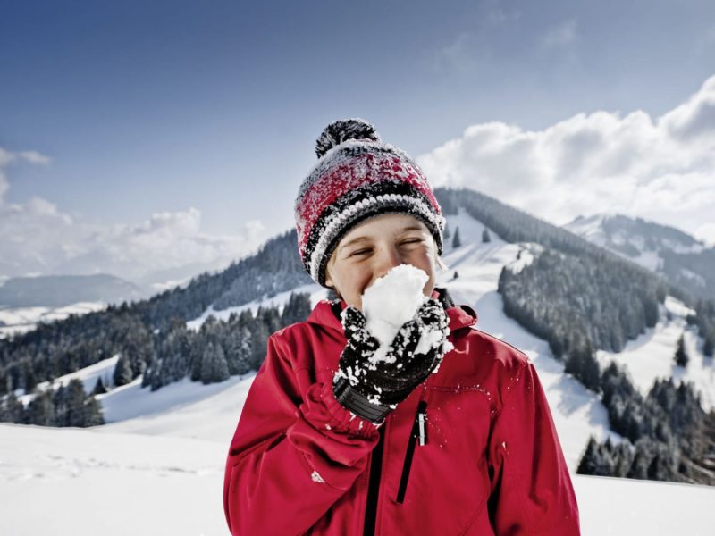 Een kind met een sneeuwbal in de Allgäuer Hörnerdörfer