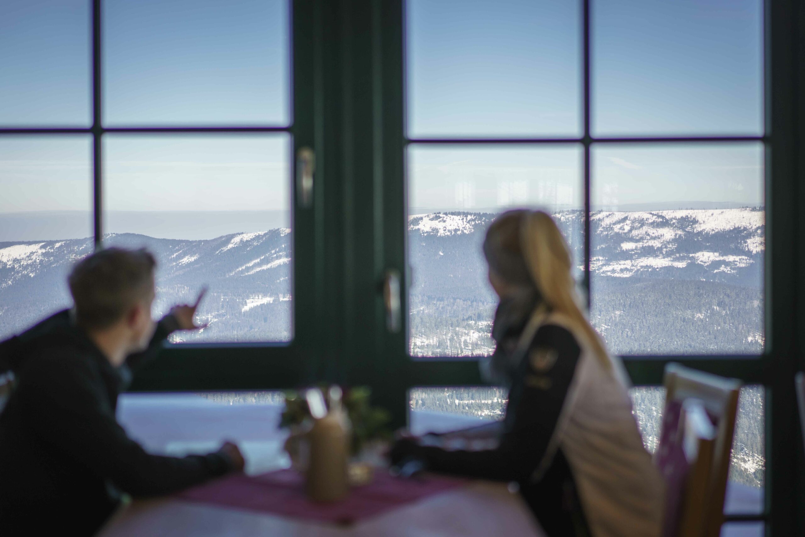 Man en vrouw kijken vanaf de Eisensteiner Hütte in het Beierse Woud op de bergen