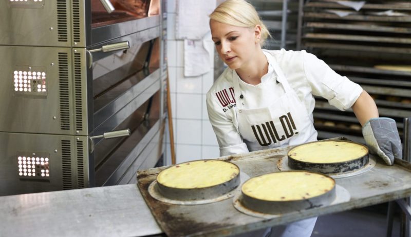 Een jonge vrouw schuift handgemaakte taarten in de oven bij Café Wild in het Bergische Land