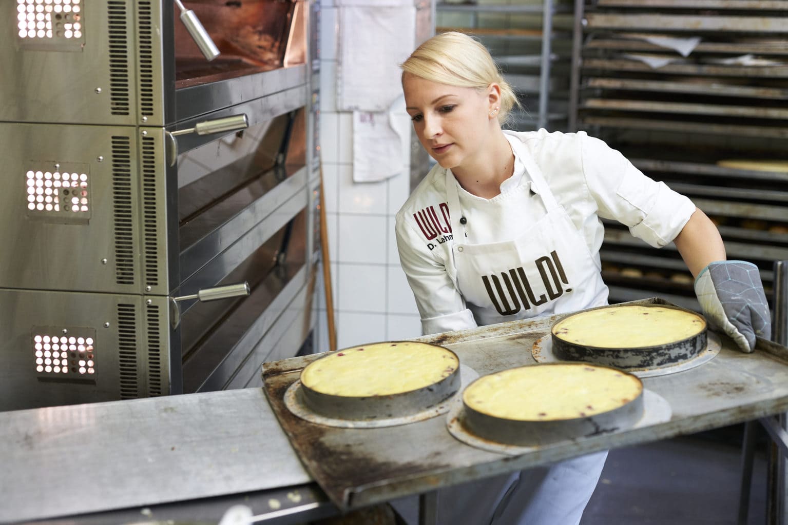 Een jonge vrouw schuift handgemaakte taarten in de oven bij Café Wild in het Bergische Land