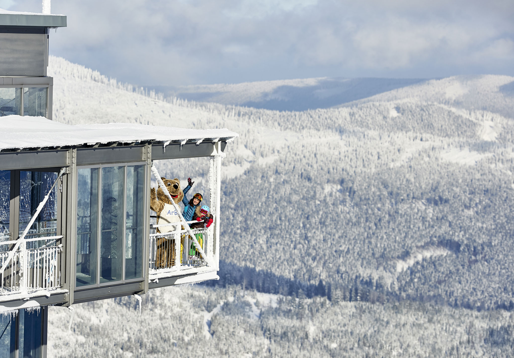 Mensen met een maskot op het balkon van een uitzichtpunt in het Beierse Woud