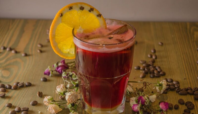 En met glühwein gevuld glas met een sinaasappelschil en andere ingredienten