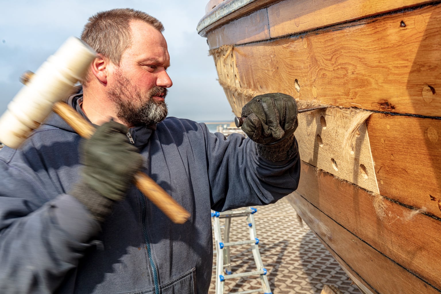 Man met hamer werkt aan zeilboot in Mecklenburg-Voor-Pommeren