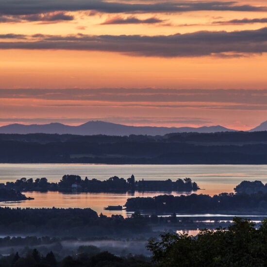 Uitzicht op de Chiemsee, de eilanden en de bergen tijdens zonsondergang