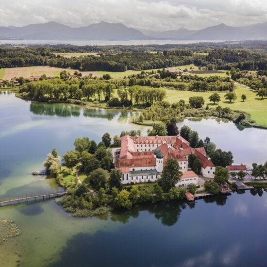 Luchtopname van Klooster Seeon op een eiland in Beieren met op de achtergrond de Alpen