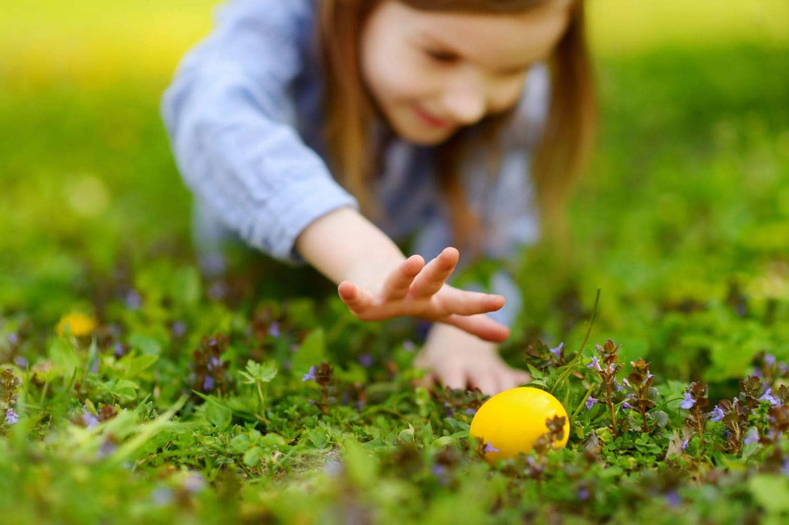 Een meisje speelt in het gras met een paasei, een Duitse traditie