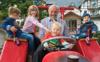 Man met kinderen op een traktoor in Familiehotel Ebbinghof in het Sauerland in Duitsland