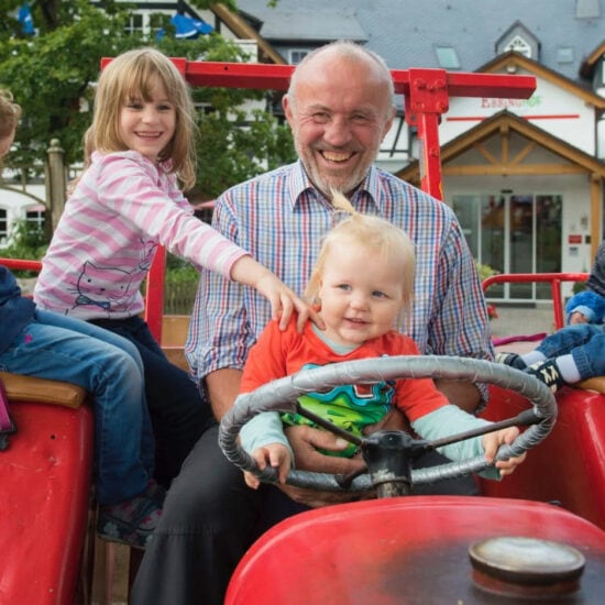 Man met kinderen op een traktoor in Familiehotel Ebbinghof in het Sauerland in Duitsland