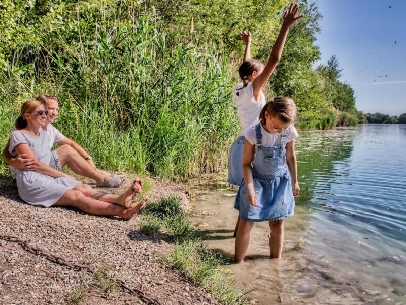 Familie zit op het Rijnstrand en geniet van de zon