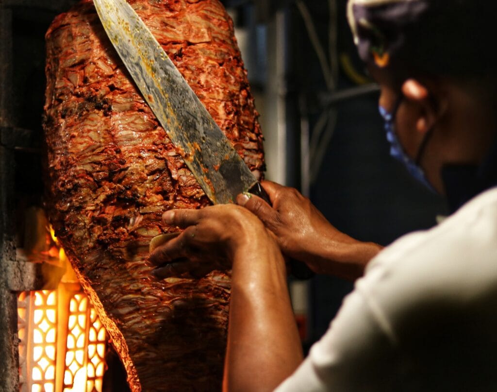 Persoon snijdt vlees van kebabspies