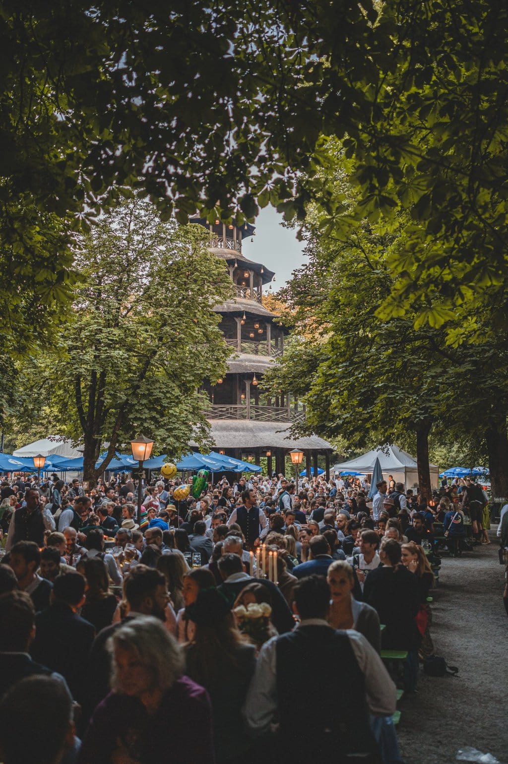 Mensen zitten bij de Chinese toren in de biertuin in de Engelse Tuin in München, Duitsland