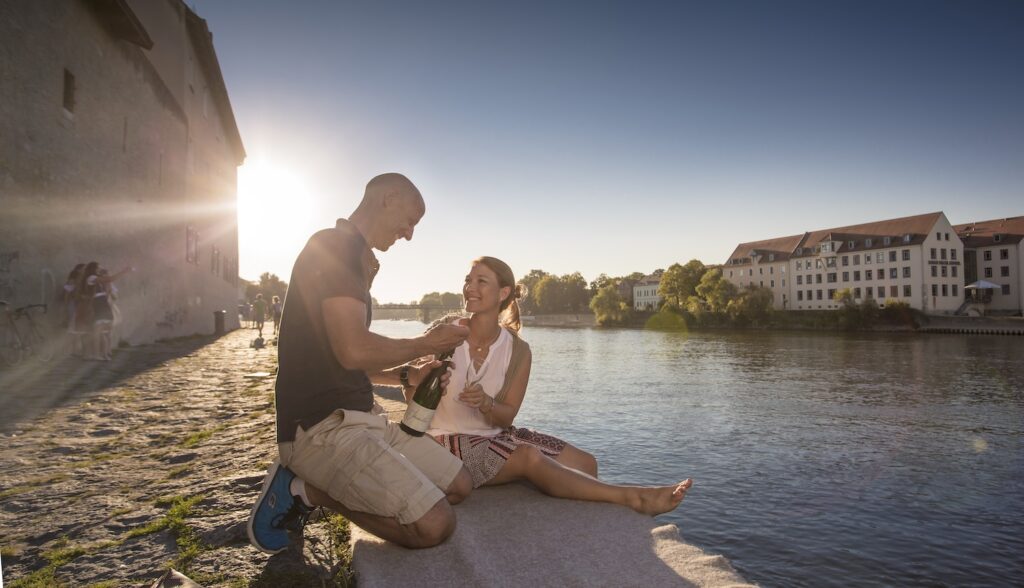 Twee mensen openen een fles champagne in Regensburg aan de Donau