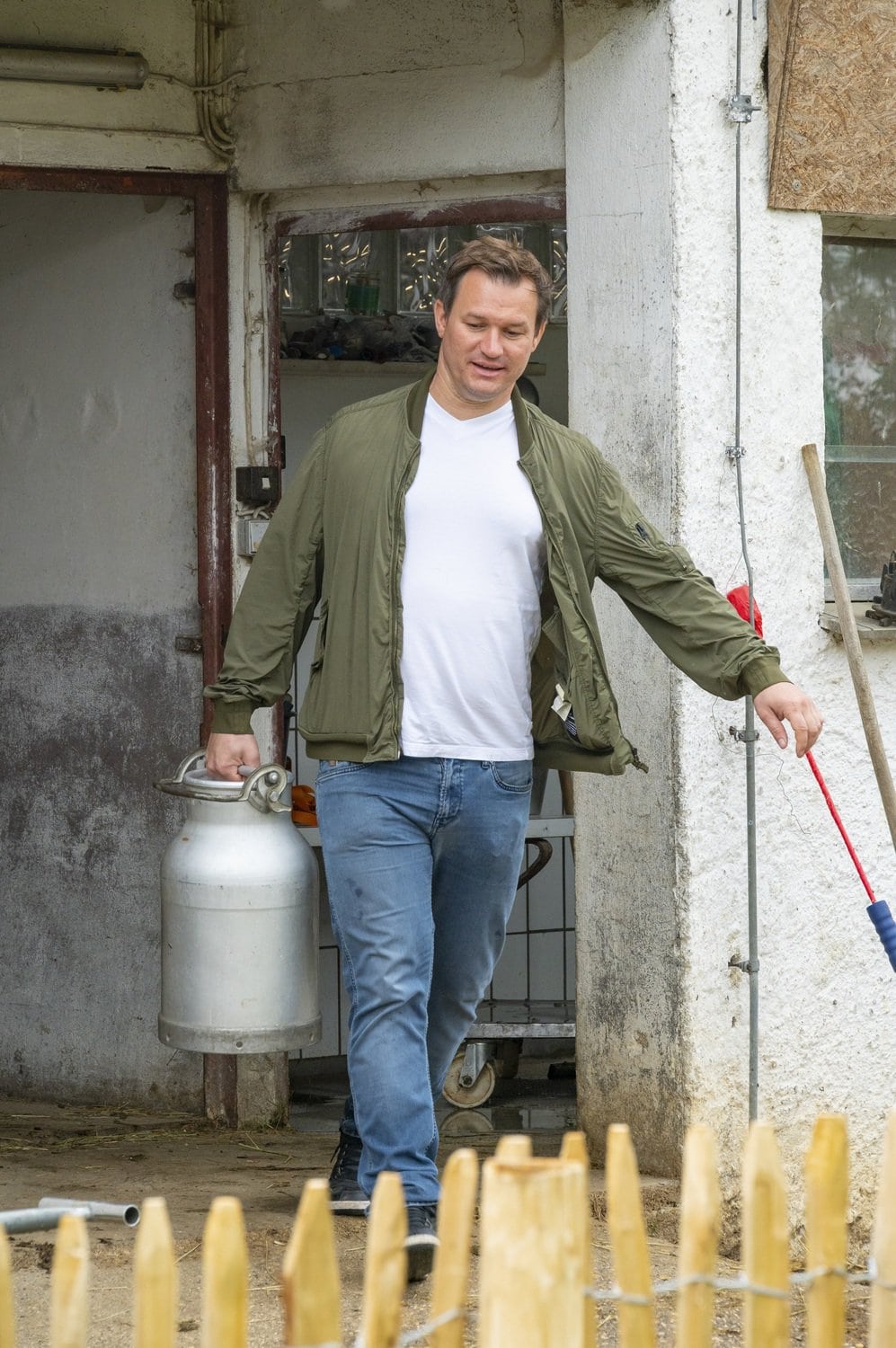 Simon Tress draagt een kan melk op de boerderij van de gebroeders Tress in Hayingen, Baden-Würrtemberg, Duitsland