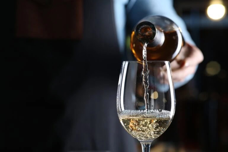 Witte wijn (Riesling) wordt in een glas geschonken