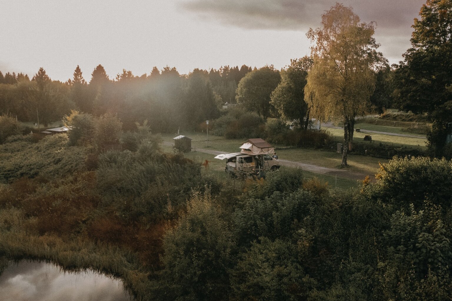 Campervan met daktent tussen herfstbomen in de Harz tijdens zonsondergang – sfeervol beeld van Wildwood Camping en vrij reizen door Duitsland.