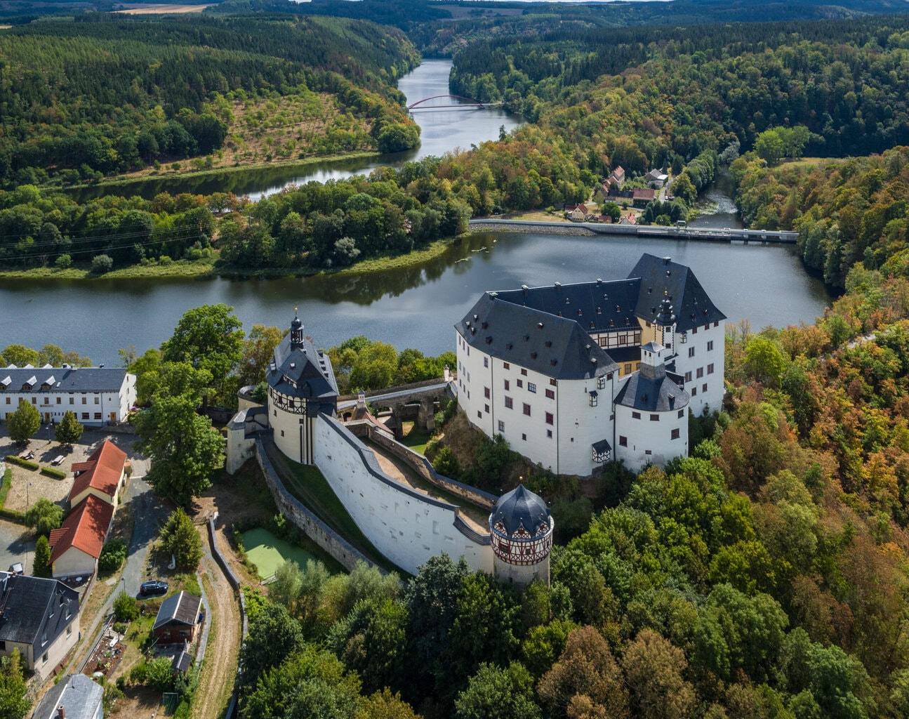Luchtfoto van een historisch kasteel aan het Thüringer Meer, omgeven door dichte bossen en het glinsterende water van het Thüringer Woud – waar cultuur en natuur elkaar ontmoeten in een betoverend landschap.