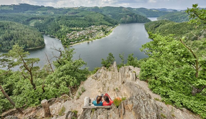 Twee wandelaars genieten van het panoramische uitzicht op het Thüringer Meer, met zijn fjordachtige bochten, dichte bossen van het Thüringer Woud en stille natuur – een paradijs voor natuurliefhebbers in Duitsland.