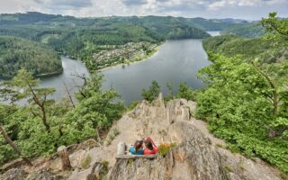 Twee wandelaars genieten van het panoramische uitzicht op het Thüringer Meer, met zijn fjordachtige bochten, dichte bossen van het Thüringer Woud en stille natuur – een paradijs voor natuurliefhebbers in Duitsland.