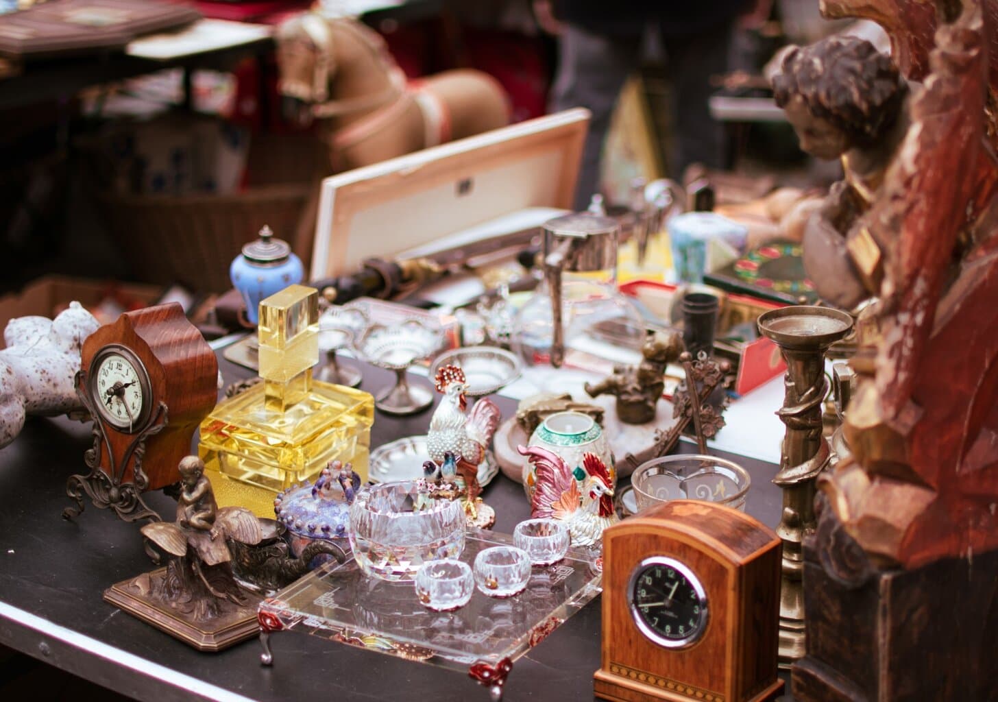 Detailopname van een kraam vol vintage klokken, kristalglas, kandelaars en porseleinen haantjes op een antiekmarkt – typisch voor de sfeervolle vlooienmarkten in Duitsland.
