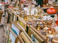 Oude schilderijlijsten, kandelaars, koperwerk, lampen en kerstdecoratie op een rommelige kraam – een typisch tafereel op sfeervolle vlooienmarkten in Duitsland, waar vintage en curiosa elkaar ontmoeten.