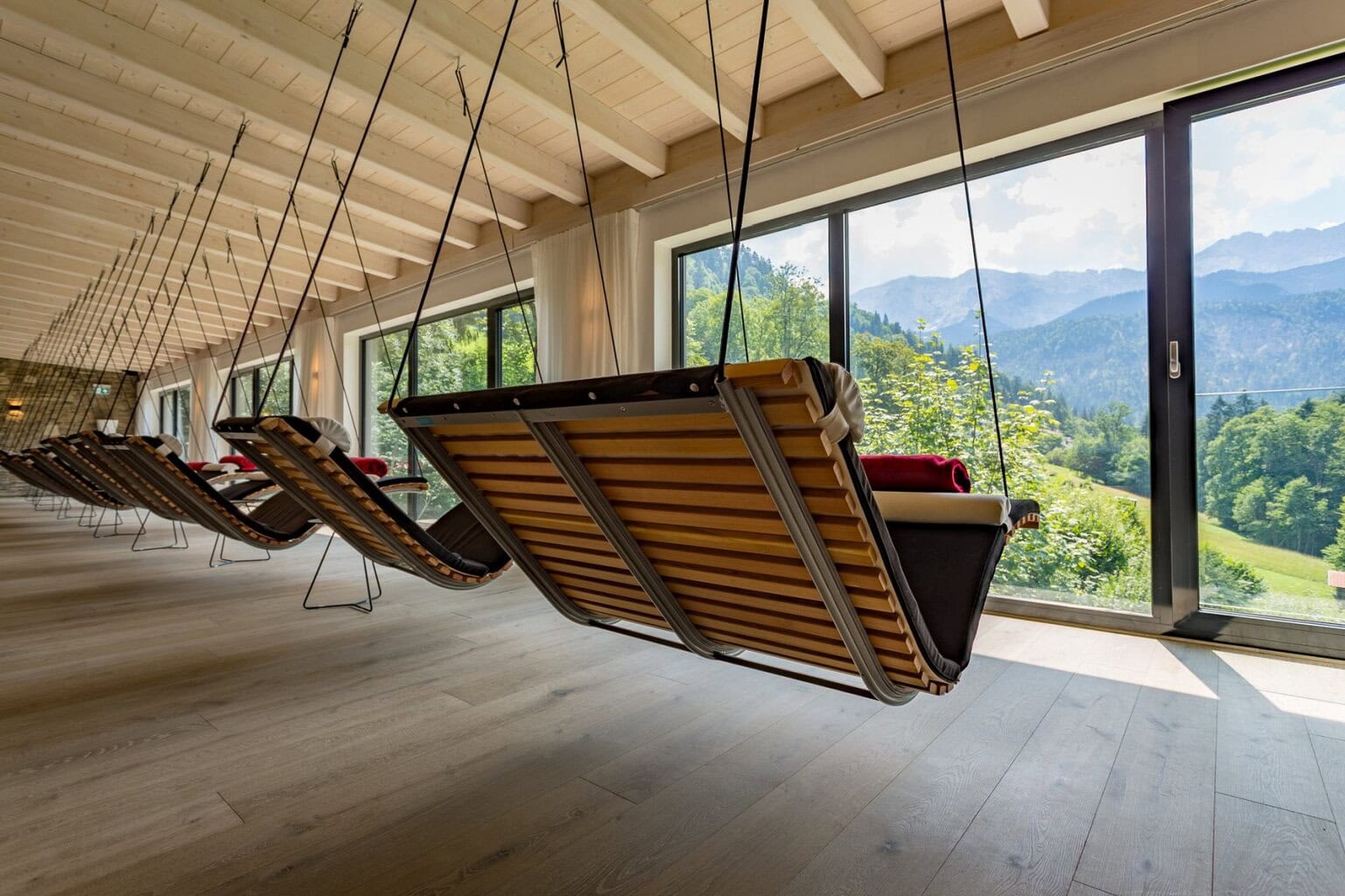 Rustige wellnessruimte in het Hotel Graseck in Beieren, met moderne schommel-ligstoelen en panoramisch uitzicht op het berglandschap. Deze unieke ontspanningszone onderstreept het natuurlijke comfort en de serene sfeer van het beste luxehotel van Duitsland, ideaal voor pure rust en bergwellness.