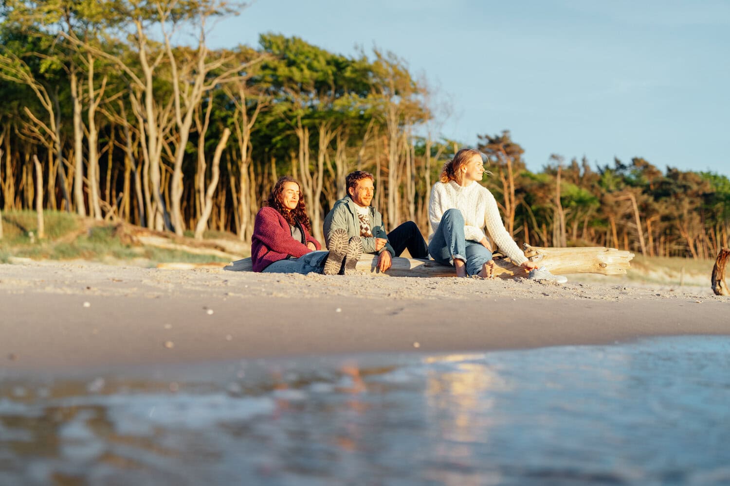 Drie Mensen zittend op het strand