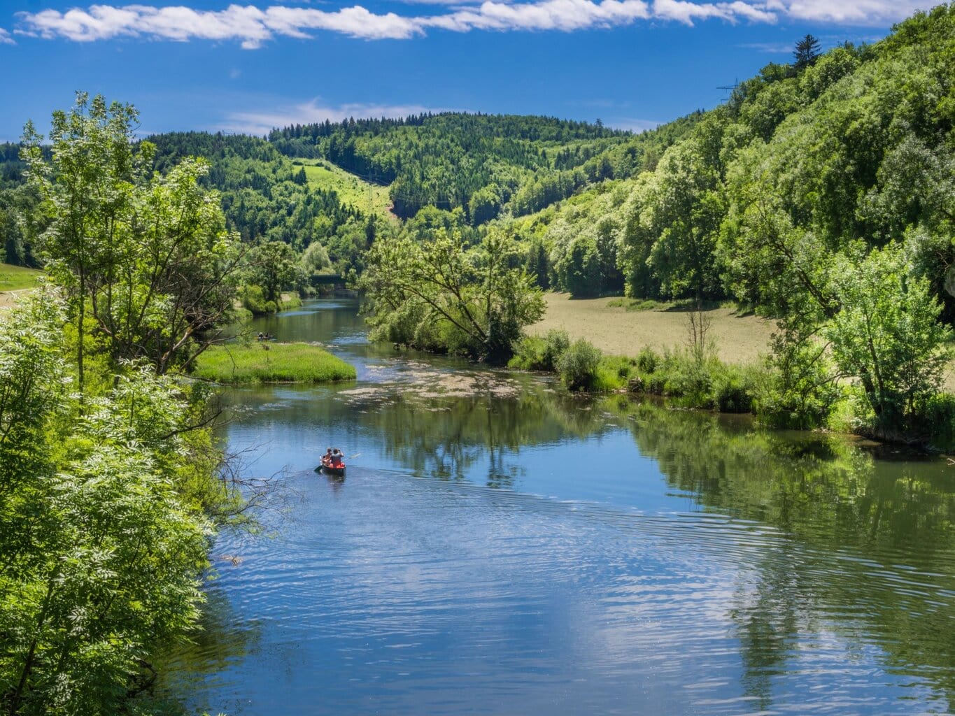 Kano op de Donau tussen groene heuvels en weides in de Zwabische Alpen – een schilderachtig decor voor een van de mooiste kanotochten Duitsland.