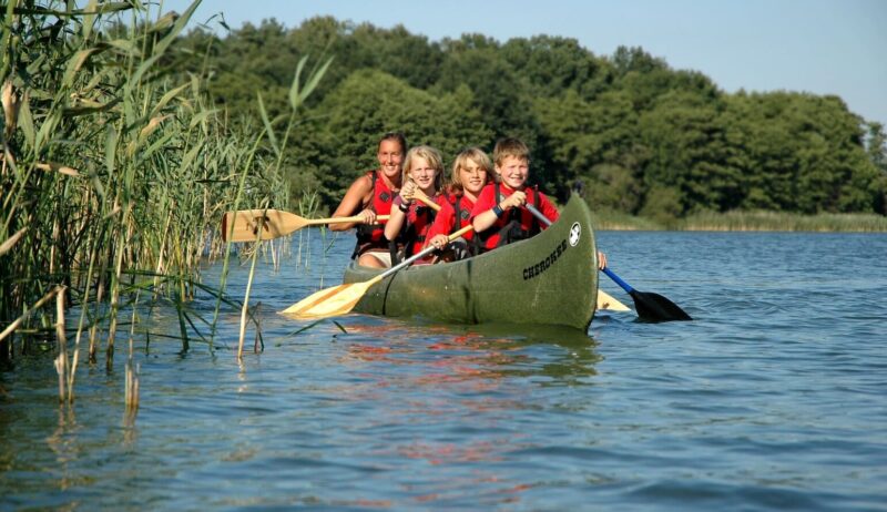 Familie vaart met een kano op een meer in het Mecklenburgse merengebied in Mecklenburg-Voor-Pommeren