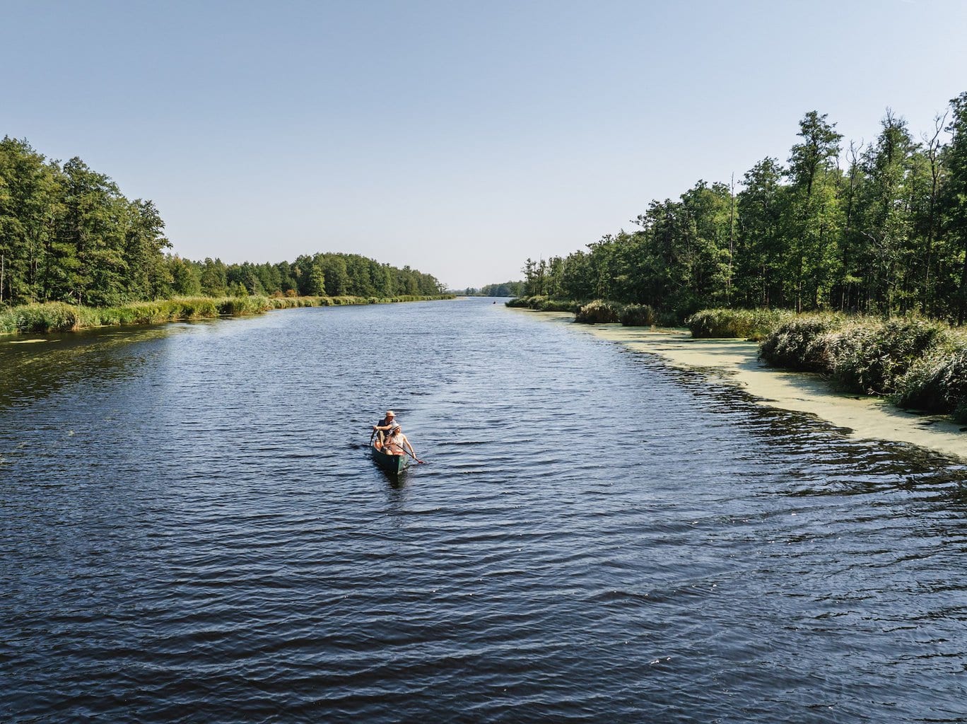 Kano op de Peene tussen groene oevers en onder een blauwe hemel – een van de stilste en meest ongerepte kanotochten Duitsland in Mecklenburg-Voor-Pommeren.