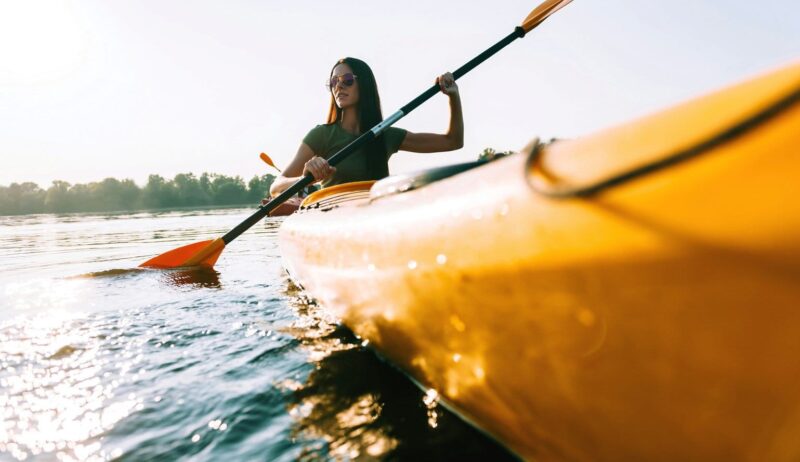 Vrouw peddelt in een gele kano over een zonovergoten rivier tijdens een zomerse tocht – een typisch moment voor actieve kanotochten Duitsland.